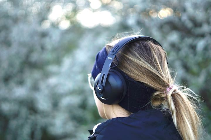 Frau mit Kopfhoerern und Stirnband in der Natur