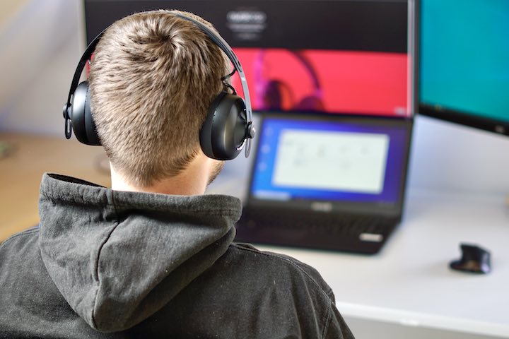 Mann sitzt mit Premium Kopfhoerern vor Computer