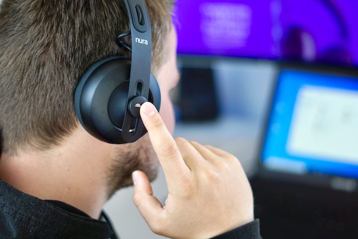 Mann tippt vor Computer auf Ohrmuschel