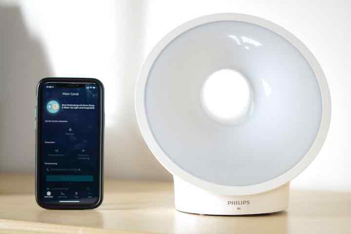 Sleep Mapper App auf iPhone steht neben einer Lampe von Philips