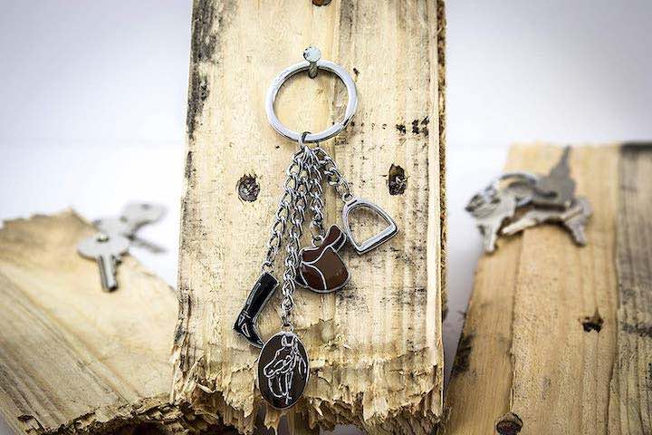 Schlüsselanhänger mit vier Reitersymbolen an Holzbrett hängend