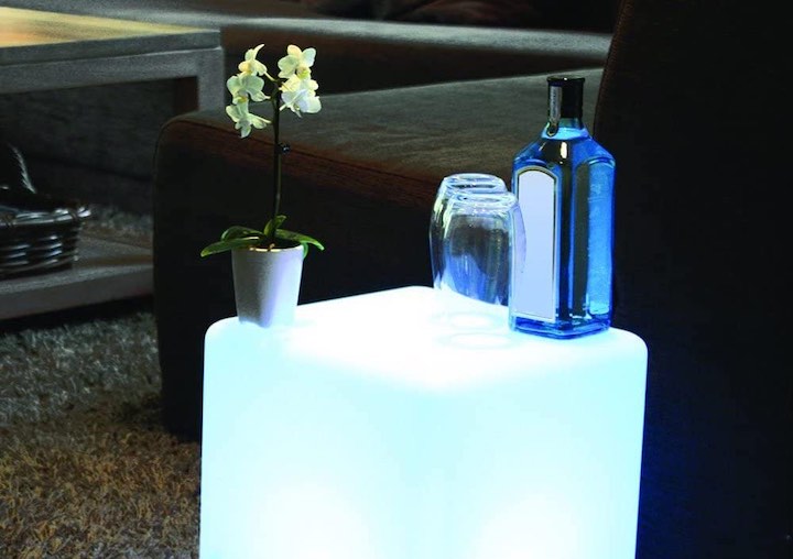 Flasche und Glas stehen auf beleuchtetem LED W%C3%BCrfel in einem Wohnzimmer