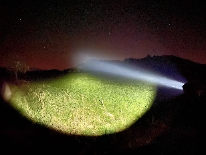 Lichtstrahl leuchtet im Dunkeln und Abendrot auf eine Wiese