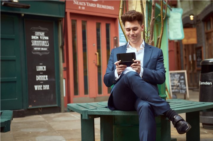 Mann sitzt auf einer Bank und schreibt mit einem Smartphone