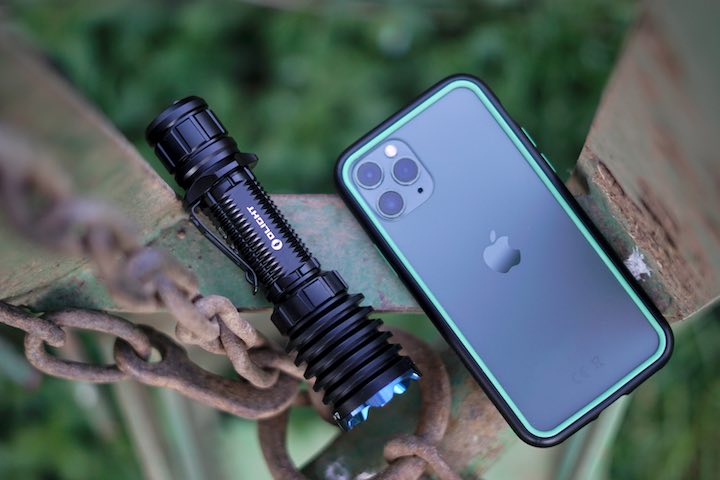 Olight Lampe liegt auf neben einem iPhone 11 Pro auf einer Metallstange