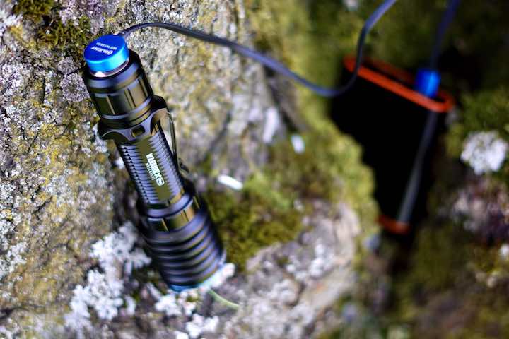 Olight Taschenlampe ist an Baum angelehnt und wird geladen