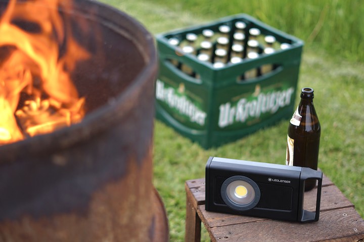 Ledlenser Baustrahler steht neben einem Feuer vor einem Bierkasten