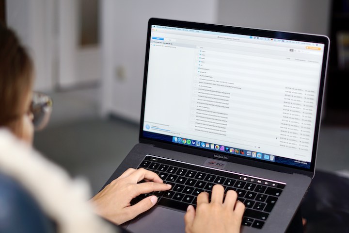 Frau tippt auf MacBook mit geoeffneter Software