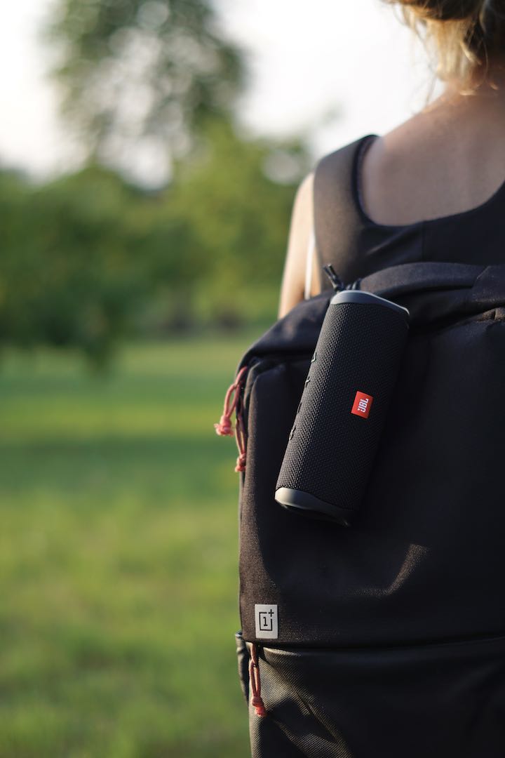 Woman with a backpack has a JBL box hanging on it