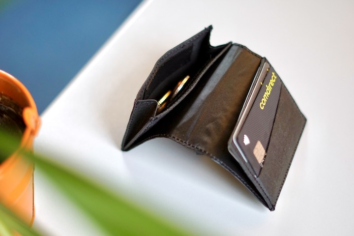 Slim Wallet mit Karten und Geld liegt neben einer Pflanze auf einem Tisch