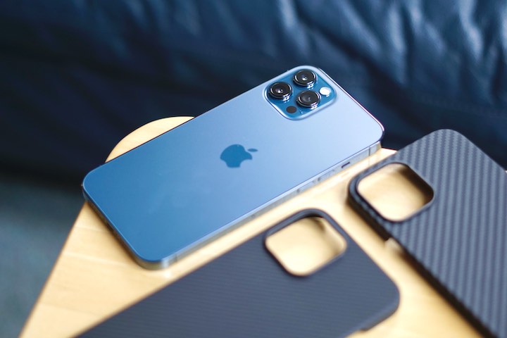 iPhone 12 Pro Max in blau liegt auf einem Tisch neben zwei Huellen