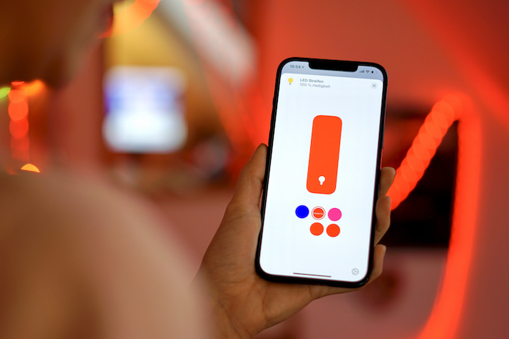 Hand mit iPhone und Apple HomeKit Farbsteuerung