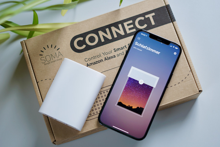 iPhone und SOMA Connect Box liegen neben einer Pflanze auf einem Karton