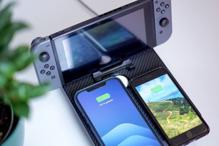 Nintendo Switch und zwei iPhones liegen auf einer Ladestation