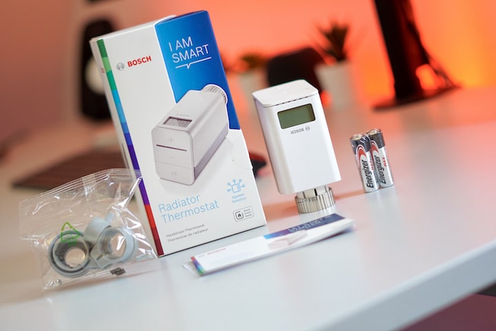 Heizungsthermostat mit Lieferumfang und Adapter vor rotem Licht