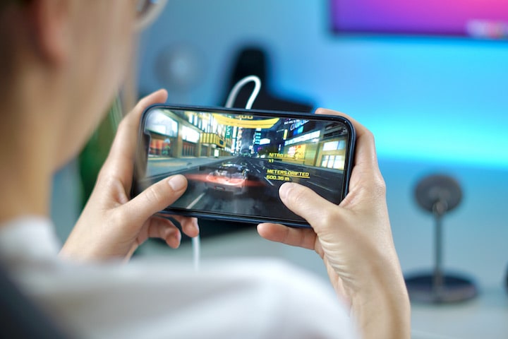 Frau mit Smartphone in der Hand spielt ein Racing Game