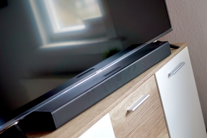 PEAQ PSB 150 Soundbar Lautsprecher liegt auf einem Schrank vor einem TV