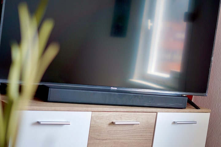 PEAQ Soundbar steht auf Sideboard neben einer Pflanze vor einem TV