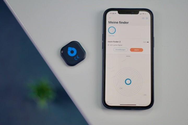 iPhone mit Tracker App liegt neben einem Bluetooth Chip