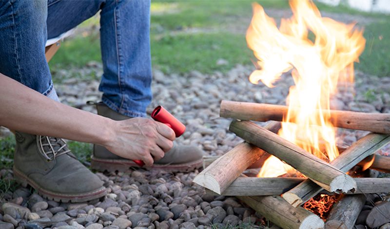 Mann entfacht ein Feuer mit Hilfe eines Foehns