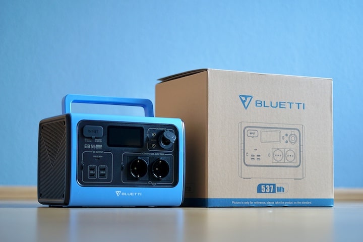 BLUETTI EB55 Powerstation steht neben Verpackung vor einer blauen Wand