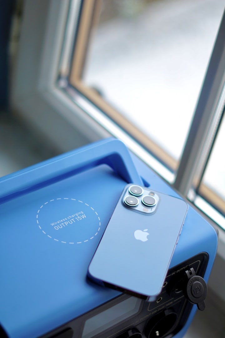 Blaues iPhone liegt neben einem kabellosen Lademodul auf einem externen Akku