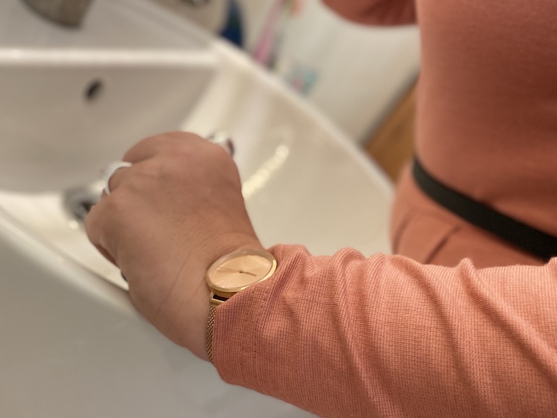 Frau mit Uhr an Waschbecken