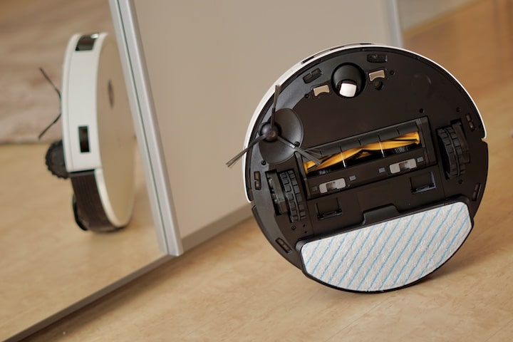 Unterseite eines Staubsauger Roboters mit Wischmodul steht vor einem Spiegel