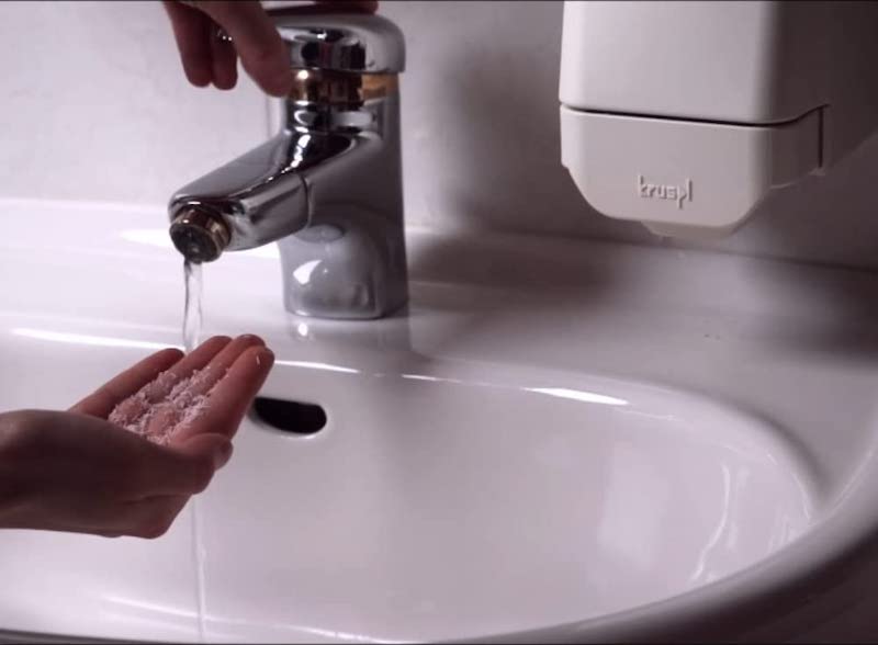 Hand mit Seifenflocken am Waschbecken