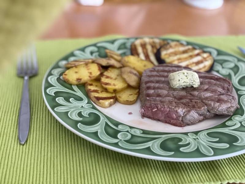 Fertiges Steak mit Kraeuterbutter und Kartoffeln