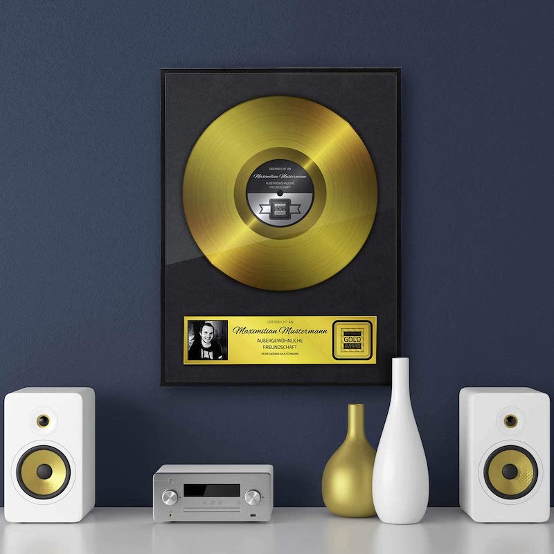 Goldene Schallplatte haengt an blauer Wand mit Deko