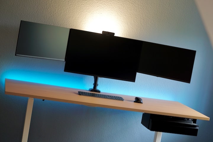 Drei Monitore auf Schreibtisch mit blauer LED Leiste