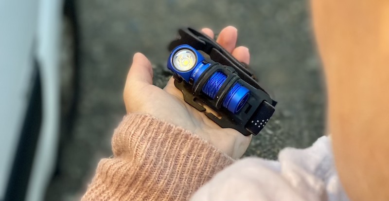 Olight Perun 2 Mini liegt mit Kopfband in Hand