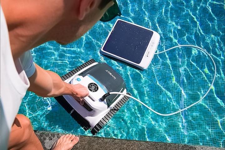 Mann hebt Reinigungsroboter in einen Pool