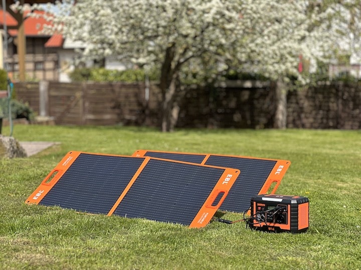 Zwei Solarpanele laden eine Powerstation in einem Garten