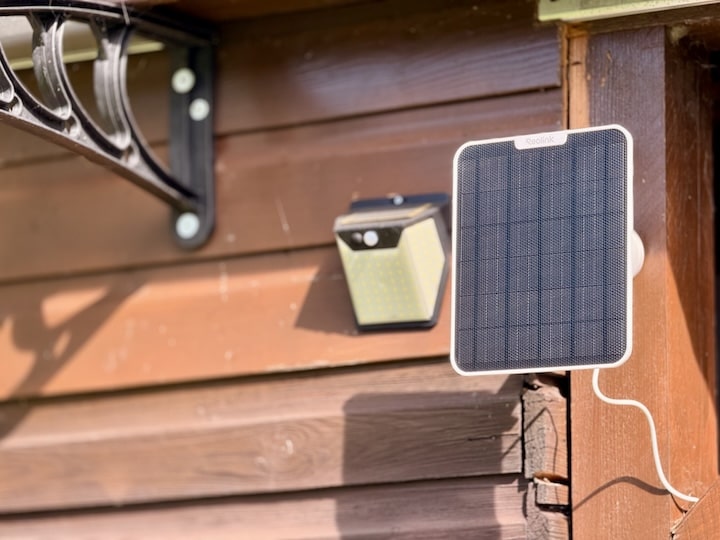 Solarpanel an einer Wand neben einer Solarlampe