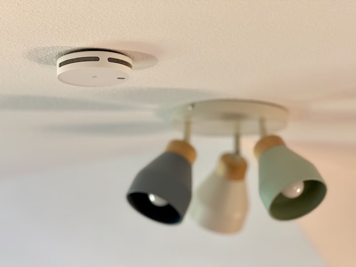 Rauchmelder an einer Decke vor einer Lampe
