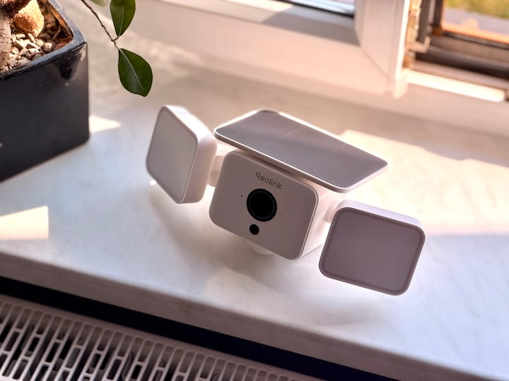 Reolink Solar Floodlight Cam: Flutlicht und Security Kamera Reolink Solar Floodlight Cam auf einem Festerbrett neben einer Pfanze